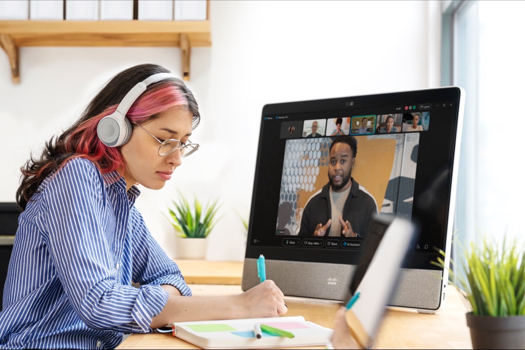 Woman with headphones taking notes during a Cisco video conference